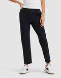 Wearing a white tank top, Cozy Earth Women's Always Cropped Pant in black, and white New Balance sneakers, a person stands with one hand on their hip against a plain background. |Color:Jet Black