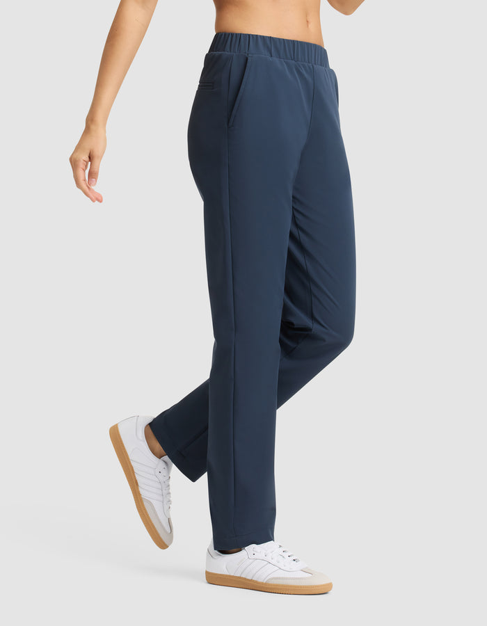 A woman models Cozy Earth's Women's Always Pant in navy blue, featuring an elastic waistband and pockets, paired with white sneakers. Only her lower torso and legs are visible against a light gray background. |Color:Eclipse