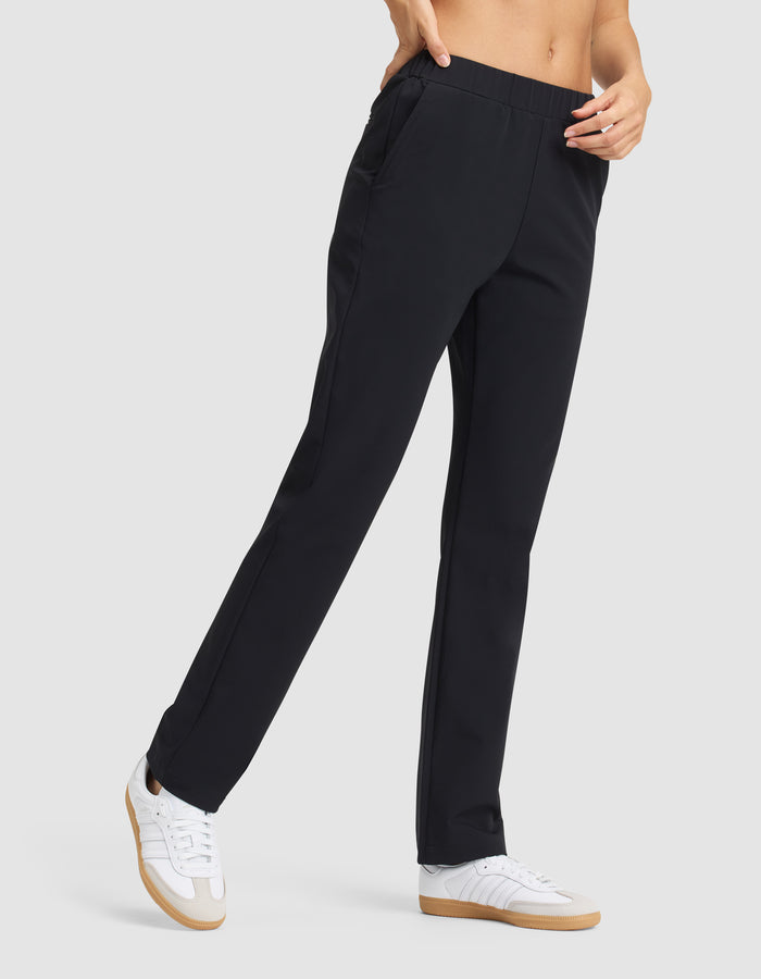 A person wearing Cozy Earth's Women's Always Pant in black and white sneakers, standing with one hand in their pocket against a plain light gray background. |Color:Jet Black