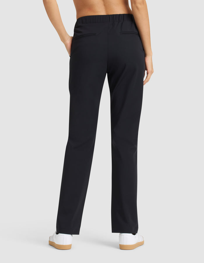 A person is shown from the back wearing Cozy Earth Women’s Always Pant in black with white sneakers, hands in pockets, against a plain light gray background. |Color:Jet Black