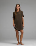 A woman stands barefoot on a plain backdrop, wearing the Cozy Earth Women’s Bamboo Rib-Knit Boyfriend Sleep Dress in brown. She faces forward with a relaxed posture and a neutral expression.|Color:Espresso