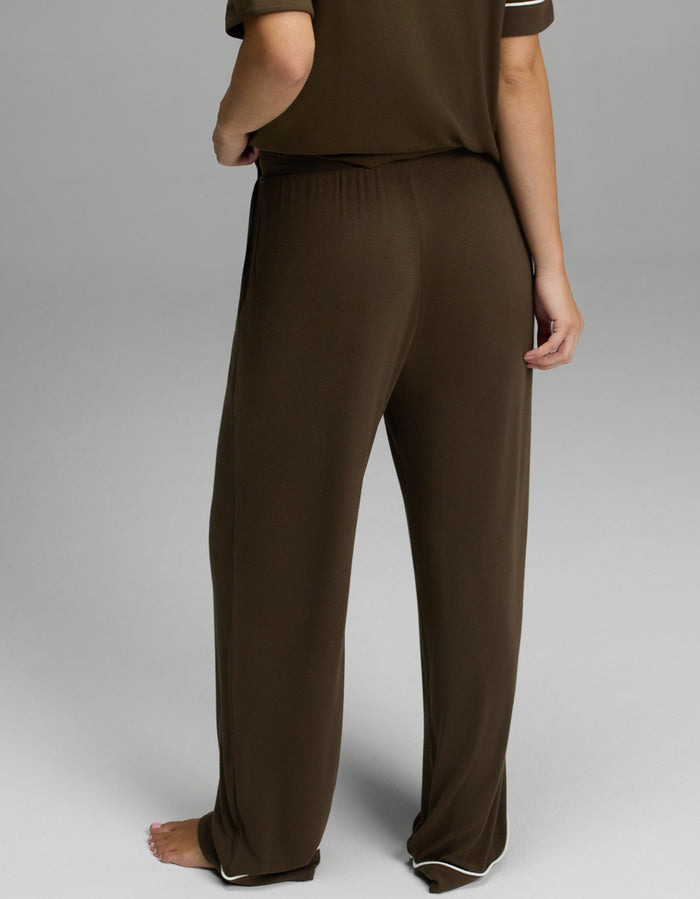 A person standing barefoot, shown from the waist down, wearing Cozy Earth’s Women’s Bamboo Rib-Knit Classic Pajama Pant in brown with a matching short-sleeve top against a plain background.|Color:Espresso