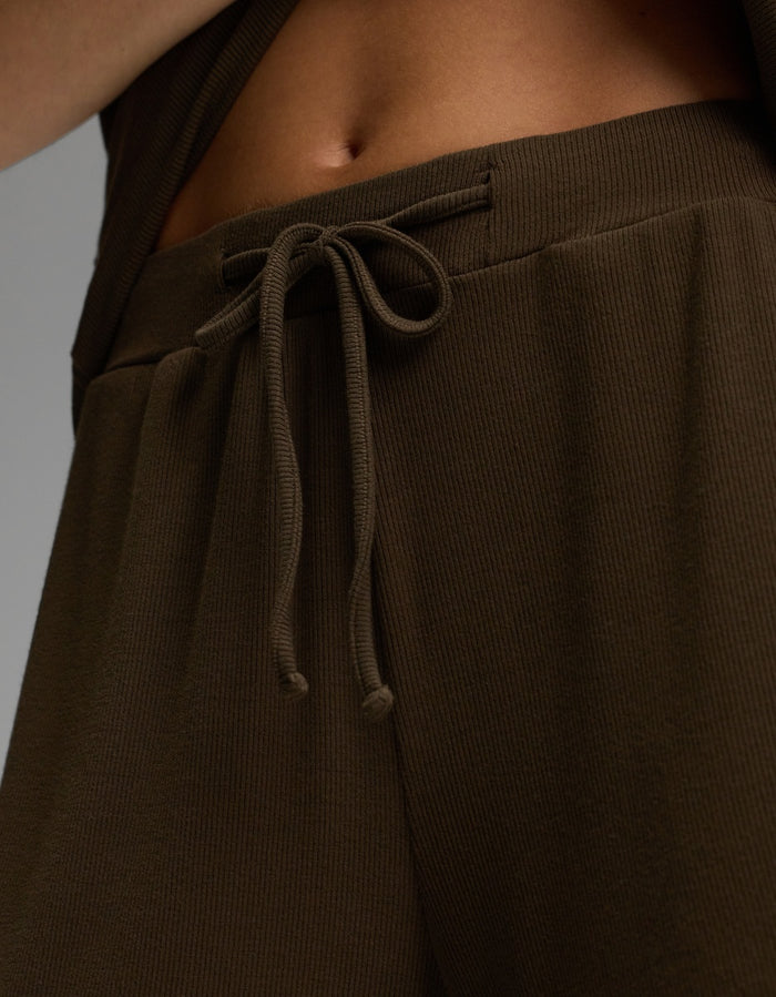 Close-up of a person wearing Cozy Earth’s Women’s Bamboo Rib-Knit Classic Pajama Short in brown. The tied drawstring and ribbed waistband are visible, along with part of the lower torso and abdomen.|Color:Espresso