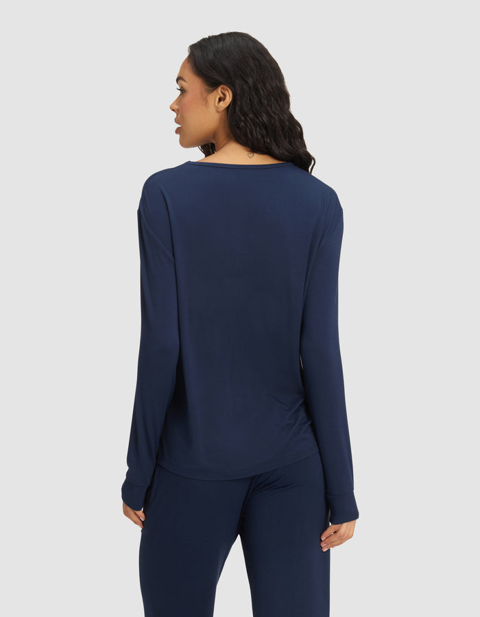 A woman with long dark hair is seen from the back, wearing the Cozy Earth Women's Bamboo Stretch-Knit Long Sleeve Lounge Tee in navy blue, standing against a plain light background.|Color:Navy