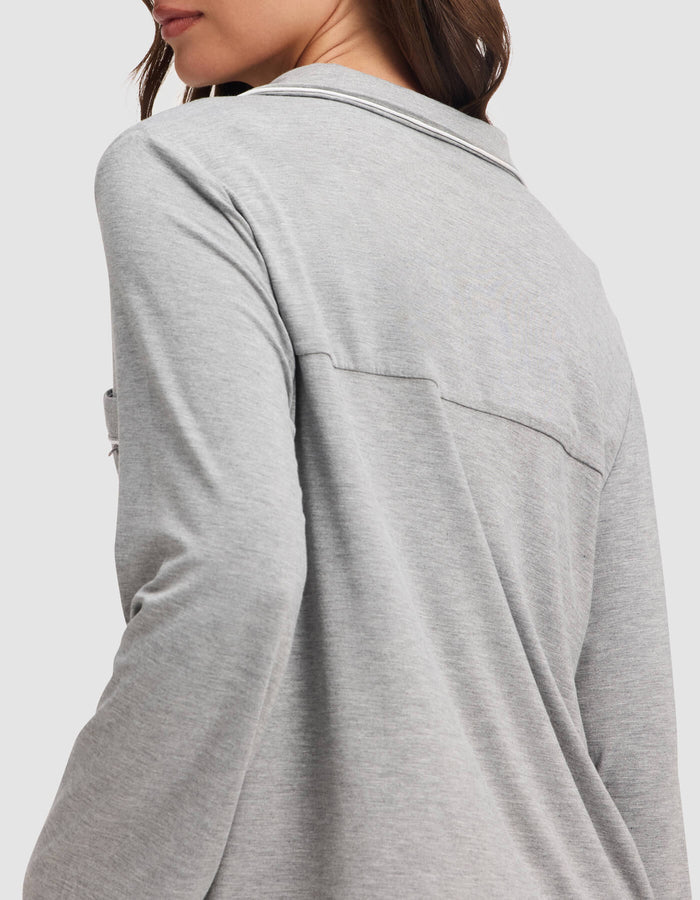 A woman is shown from the back and side wearing the Cozy Earth Women's Bamboo Stretch-Knit Long Sleeve Pajama Top in light gray, highlighting its relaxed fit and soft, stretchy fabric across the upper back and shoulders.|Color:Grey