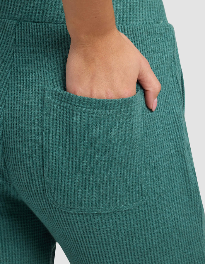 Close-up of a hand resting in the back pocket of Cozy Earth's Women's Blake Waffle Jogger in teal green, showcasing the ribbed knit texture and detailed stitching.|Color:Sea Green