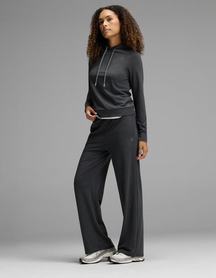 A person stands posing in a Cozy Earth Women’s Brushed Bamboo Hoodie, styled with matching wide-leg pants and silver athletic shoes, against a plain gray background.|Color:Charcoal