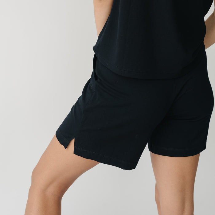 Woman wearing a black t-shirt and black Cozy Earth Brushed Bamboo Mid-Length Shorts shorts on a plain background |Color:Black