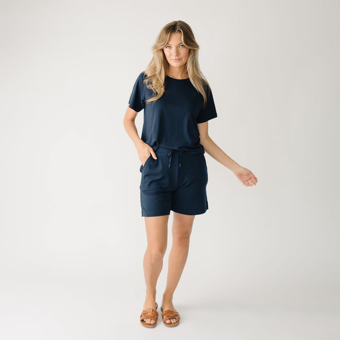 Woman wearing a navy t-shirt and navy Cozy Earth Brushed Bamboo Mid-Length Shorts shorts on a plain background |Color:Navy