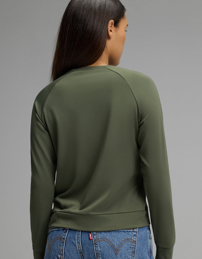 A person with long brown hair is shown from the back, wearing the Cozy Earth Women’s Brushed Bamboo Pullover Crew in olive green and blue jeans against a plain gray background.|Color:Olive