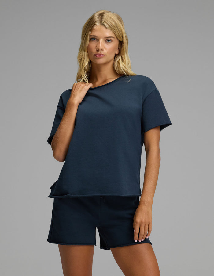 A woman with blonde hair wears the Cozy Earth Women’s Chelsea Short Sleeve Set in Eclipse, standing against a plain gray background and looking at the camera with a relaxed expression.|Color:Eclipse