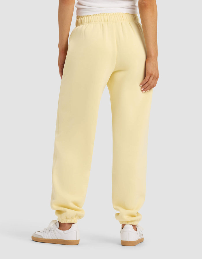 A woman is shown from the back wearing Cozy Earth’s Women's Cityscape Sweatpant in light yellow, paired with a white top and white sneakers, standing against a plain light gray background.|Color:Meringue
