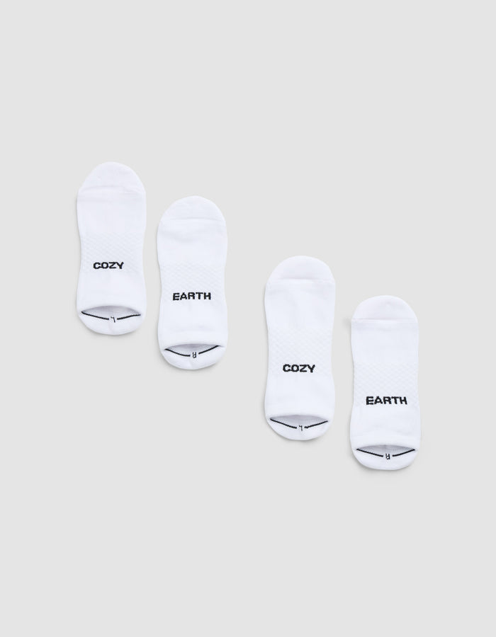 Two pairs of Cozy Earth Essential Ankle Socks are displayed side by side on a light gray background, each featuring black text near the toes—one in each pair reads "COZY" and the other reads "EARTH. |Color:White