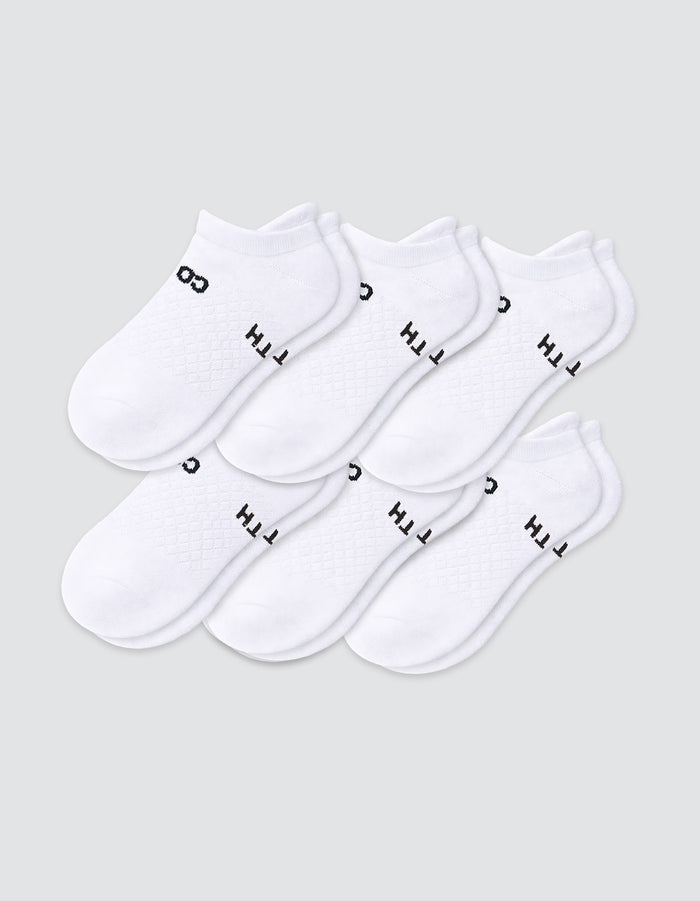 Six pairs of Cozy Earth Women's Essential Ankle Socks in white, featuring black text near the elastic opening, are arranged in two overlapping rows on a light gray background.|Color:White