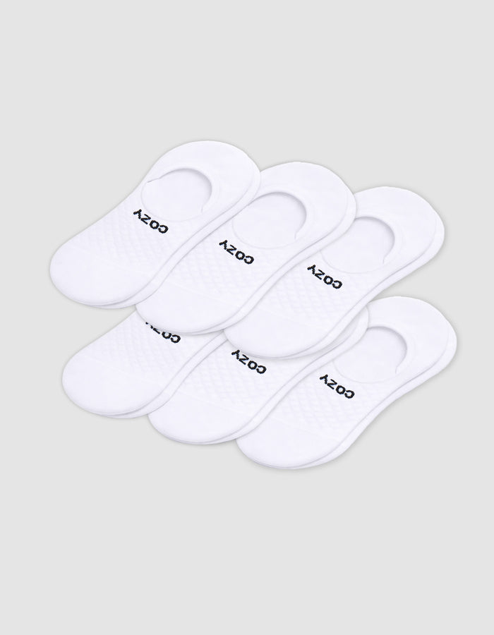 Six pairs of Cozy Earth Men's Essential No-Show Socks are stacked on a plain white background, each featuring "COZY" printed in black near the heel opening.|Color:White