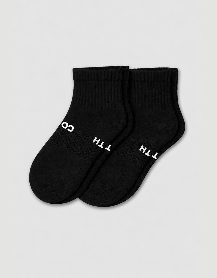 The Cozy Earth Men's Essential Quarter Sock features black ribbed cuffs and a discreet white text design on the sides, displayed against a plain light background.|Color:Black