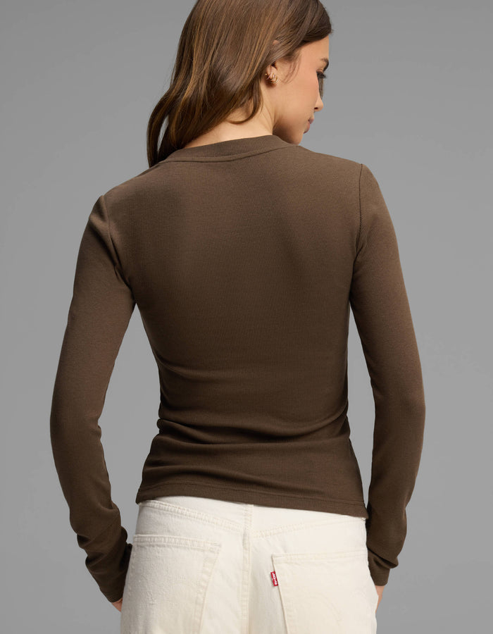 A woman with brown hair, wearing the Cozy Earth Women's Fine Ribbed Long Sleeve Tee in brown and white jeans, is standing with her back to the camera against a plain gray background.|Color:Espresso