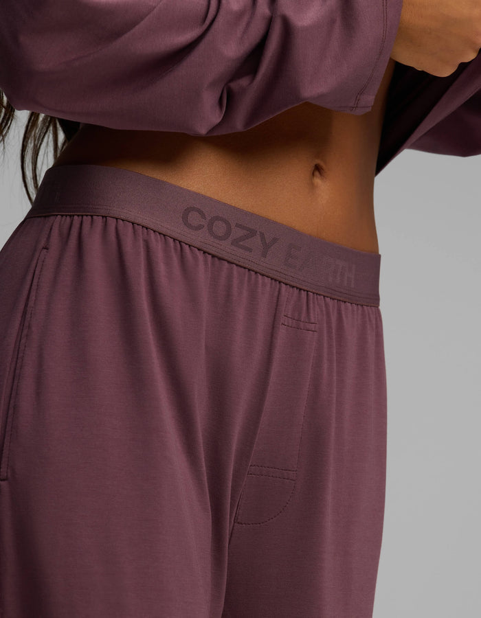A close-up of a person wearing Cozy Earth Women’s First Layer Pajama Pants in mauve with a matching top, highlighting the waistband and partial midriff.|Color:Fig