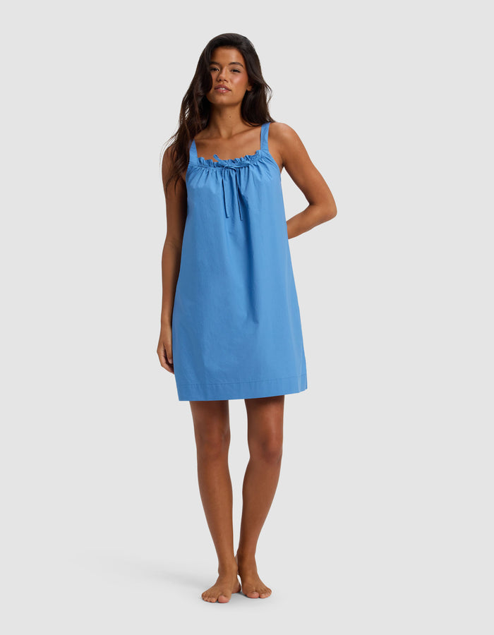 A woman stands barefoot against a plain background, wearing the Cozy Earth Women's Sutton Tank Sleep Dress in Sailor—a loose-fitting, sleeveless style with gathered neckline detail and thin shoulder straps.|Color:Sailor