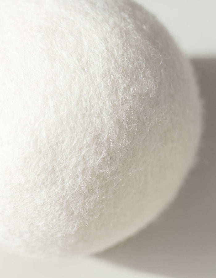 A close-up of a white, round Cozy Earth Wool Dryer Ball with a soft, fuzzy texture and light shadow on a white background.|Size:Large