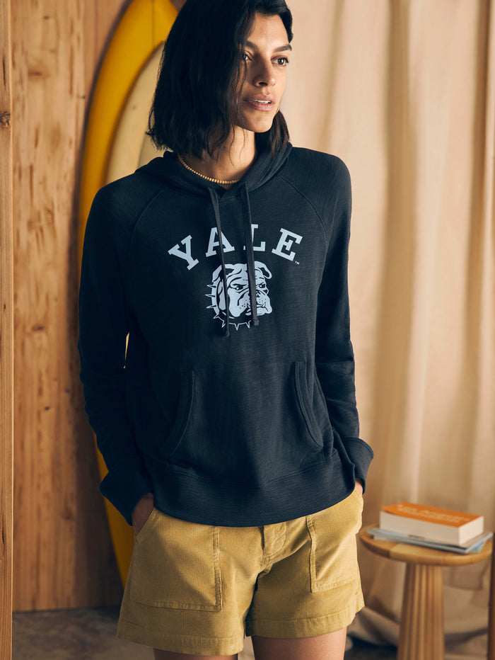 Woman wearing a black hoodie with Yale graphic at the center front in a casual setting